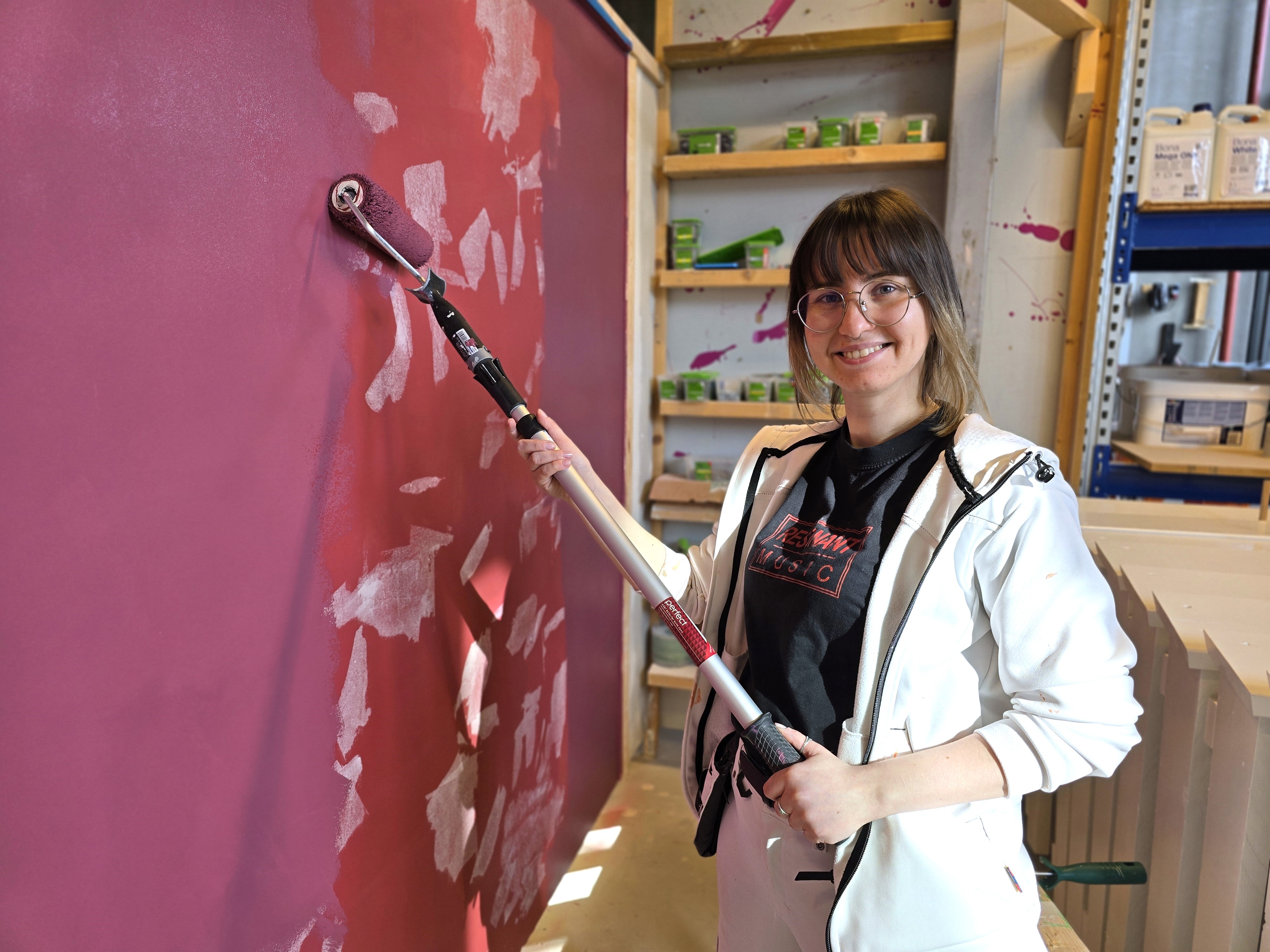 Dame som maler på en vegg.