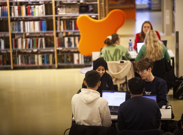 Elever som sitter ved bord og har laptop åpne.