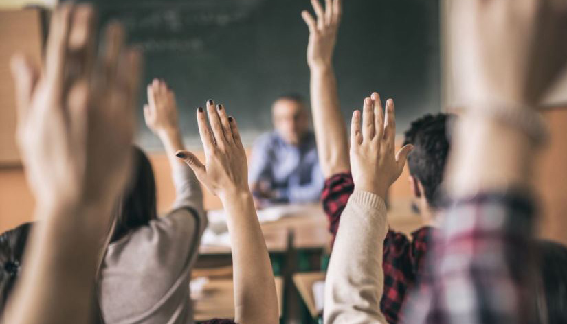 Elever som strekker opp hendene.
