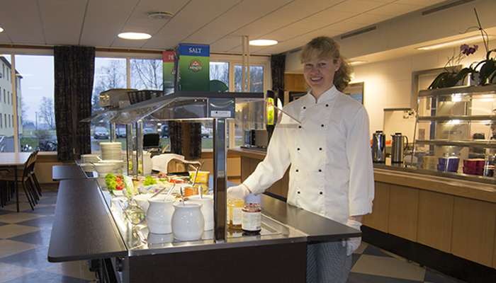 Kvinnelig kantineansatt ved buffétdisken i kantina