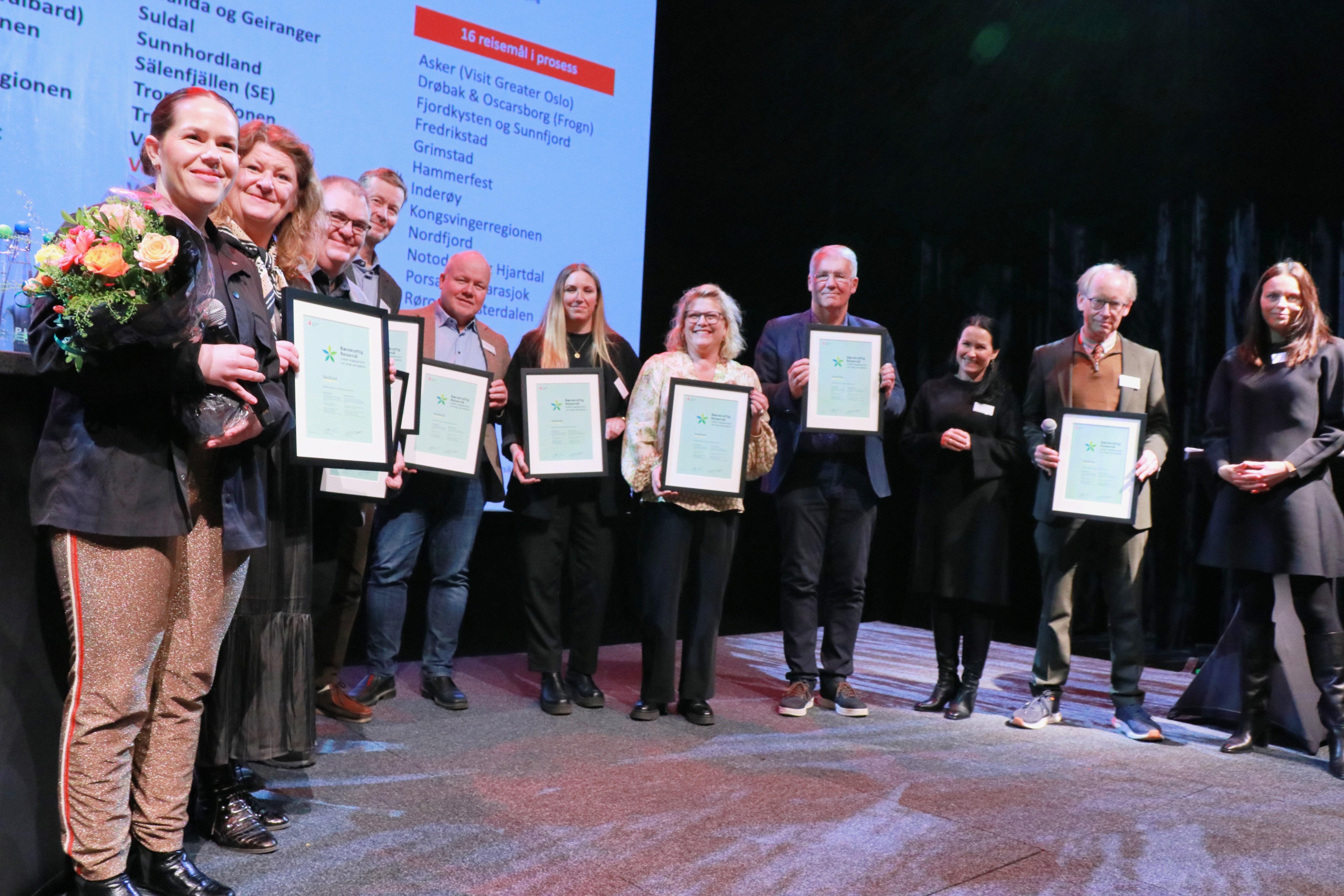 En gruppe mennesker med diplom står på en scene