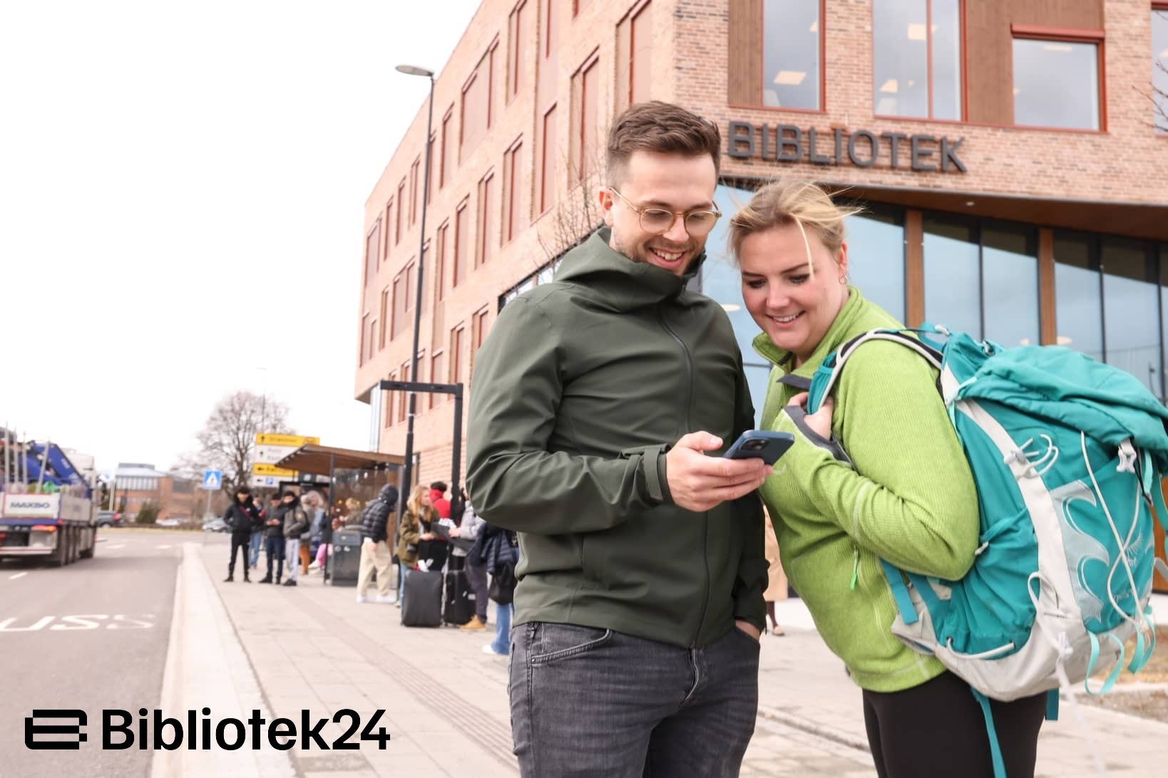 To personer som leser på en telefon utenfor et bibliotek