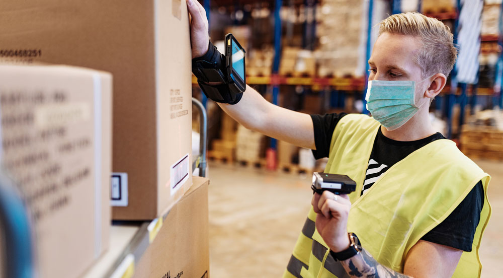 Mann jobber på lager med munnbind