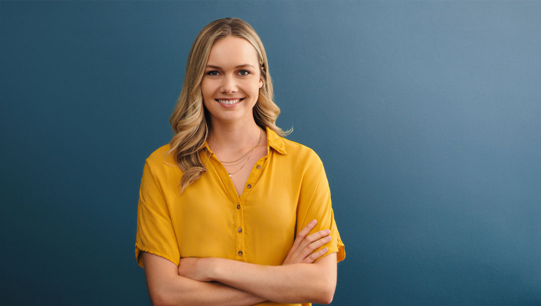 Jente i gul bluse foran blå bakgrunn