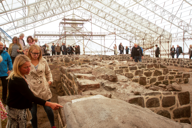 folk som studerer restaurerte ruiner i et telt