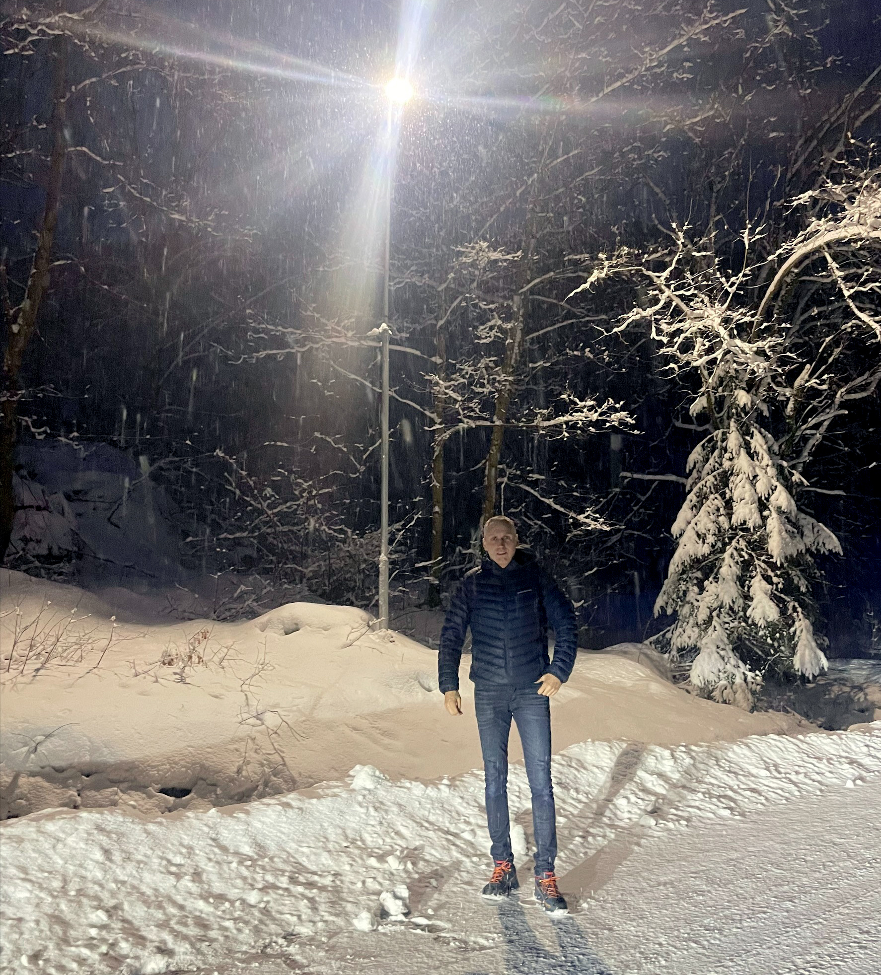 Mann står under gatelykt. Snødekt landskap omkranser.