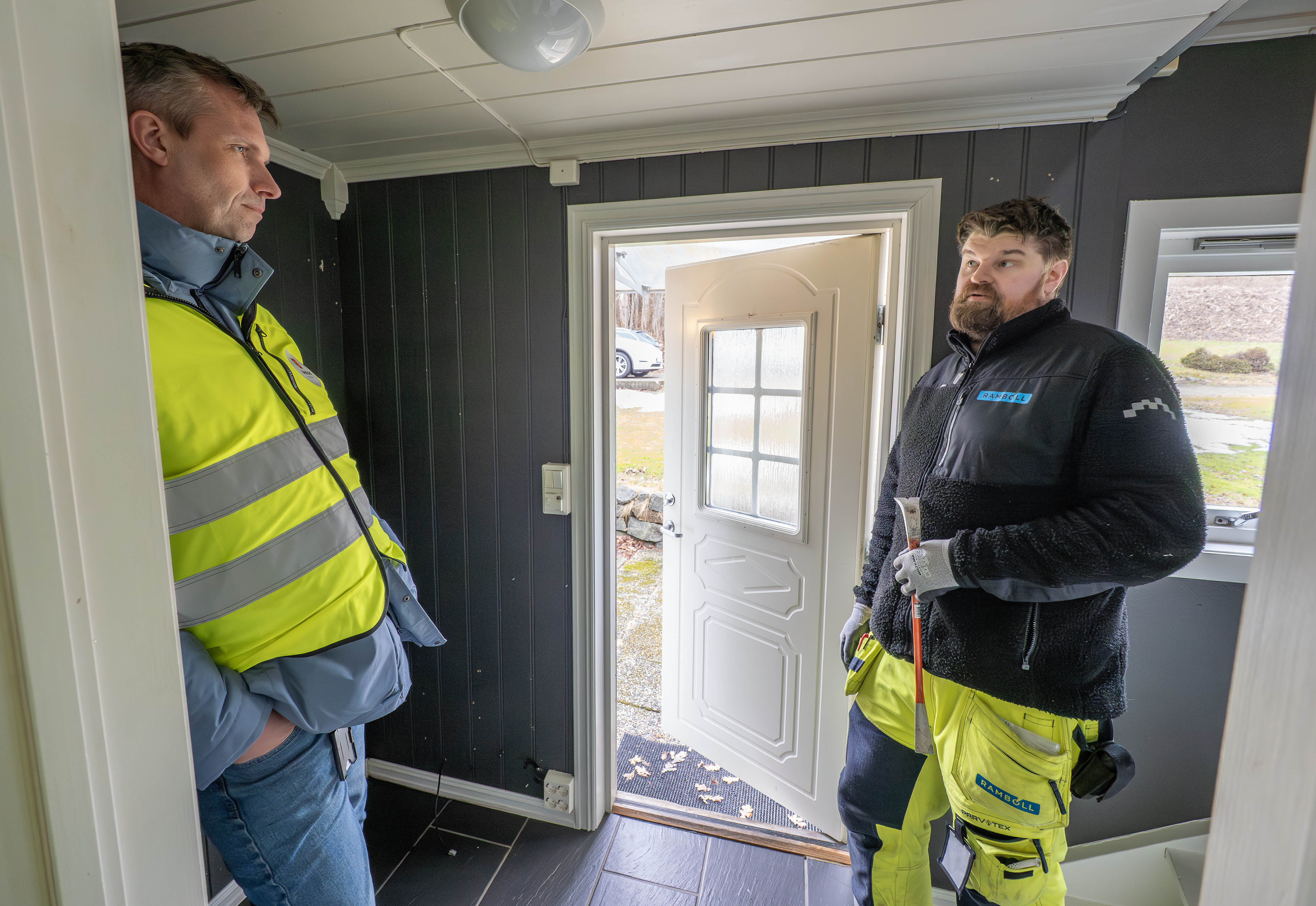 To personer står i gangen til et hus som skal rives i Eikeveien i Færder kommune.