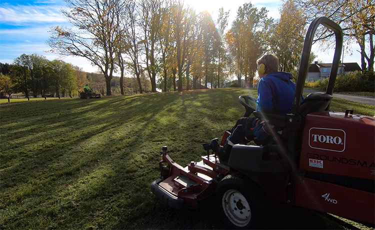 Elev kjører gressklipper på plenen
