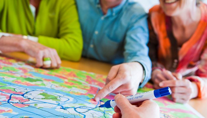 Møtesituasjon med personer og hender som tegner på kart