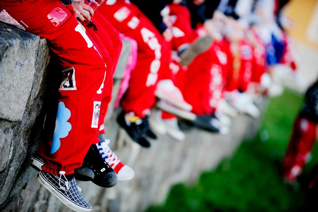 Dekorativt bilde av buksebeina til russ som sitter på et steingjerde.