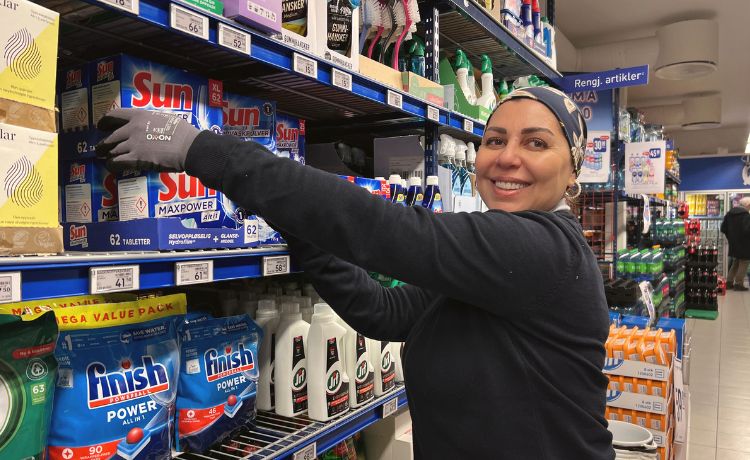 Kvinne som rydder i hylle på Rema 1000.