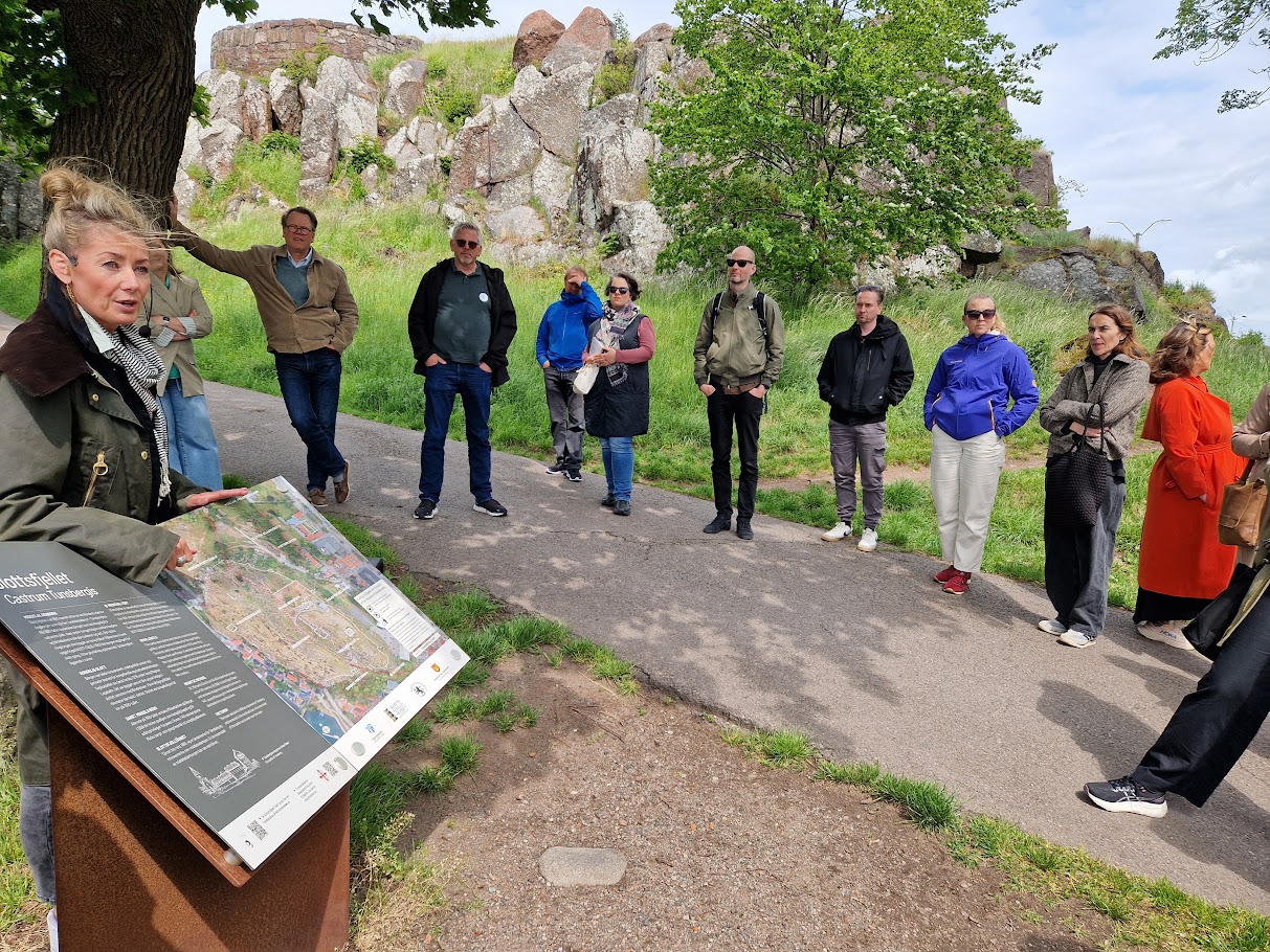 Deltakere på kulturmiljøsamling går en rundtur og får guiding på vei opp Slottsfjellet.