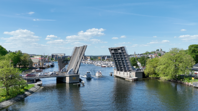 Kanalbrua Tønsberg i åpen stilling med to båter som seiler under og biltrafikk som venter på å få kjøre over brua.