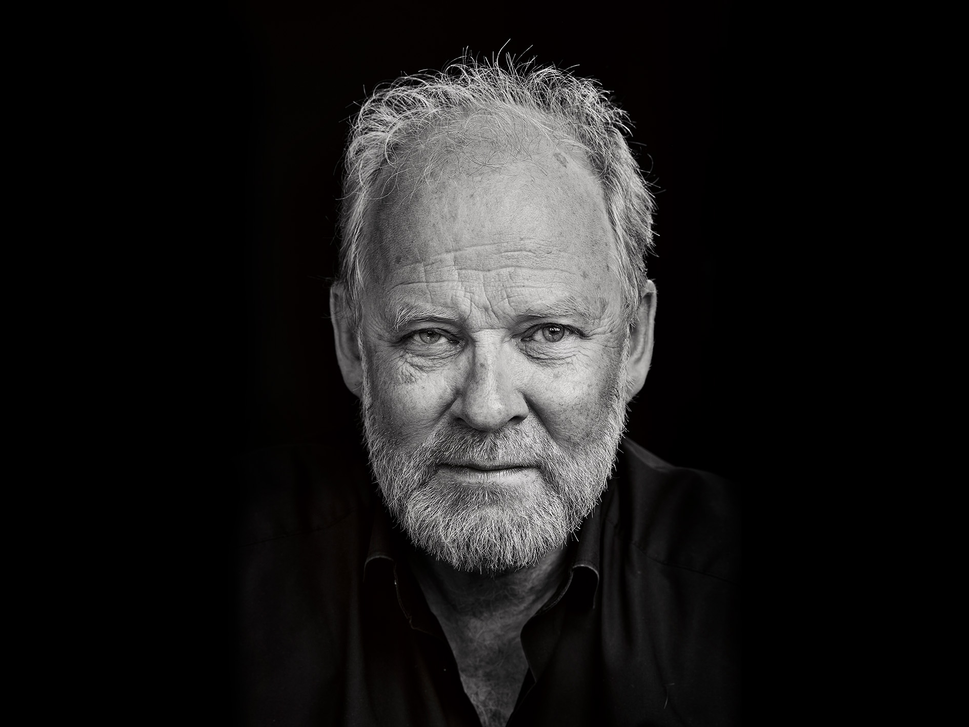 Bilde av forfatteren i sort hvitt til høyre, satt inn på et bilde av en stor bokstabel til høyre på et bord.