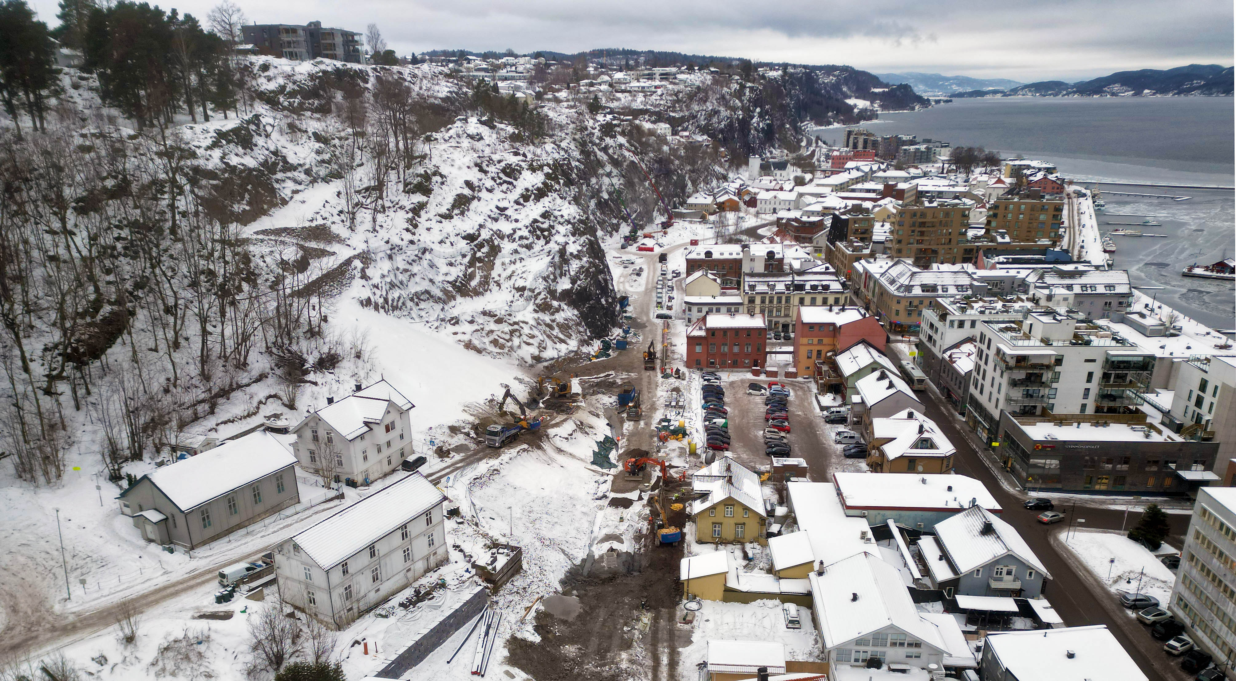 Foto av Holmestrand sentrum og gravearbeid i vinterdrakt tatt fra syd og nordover.