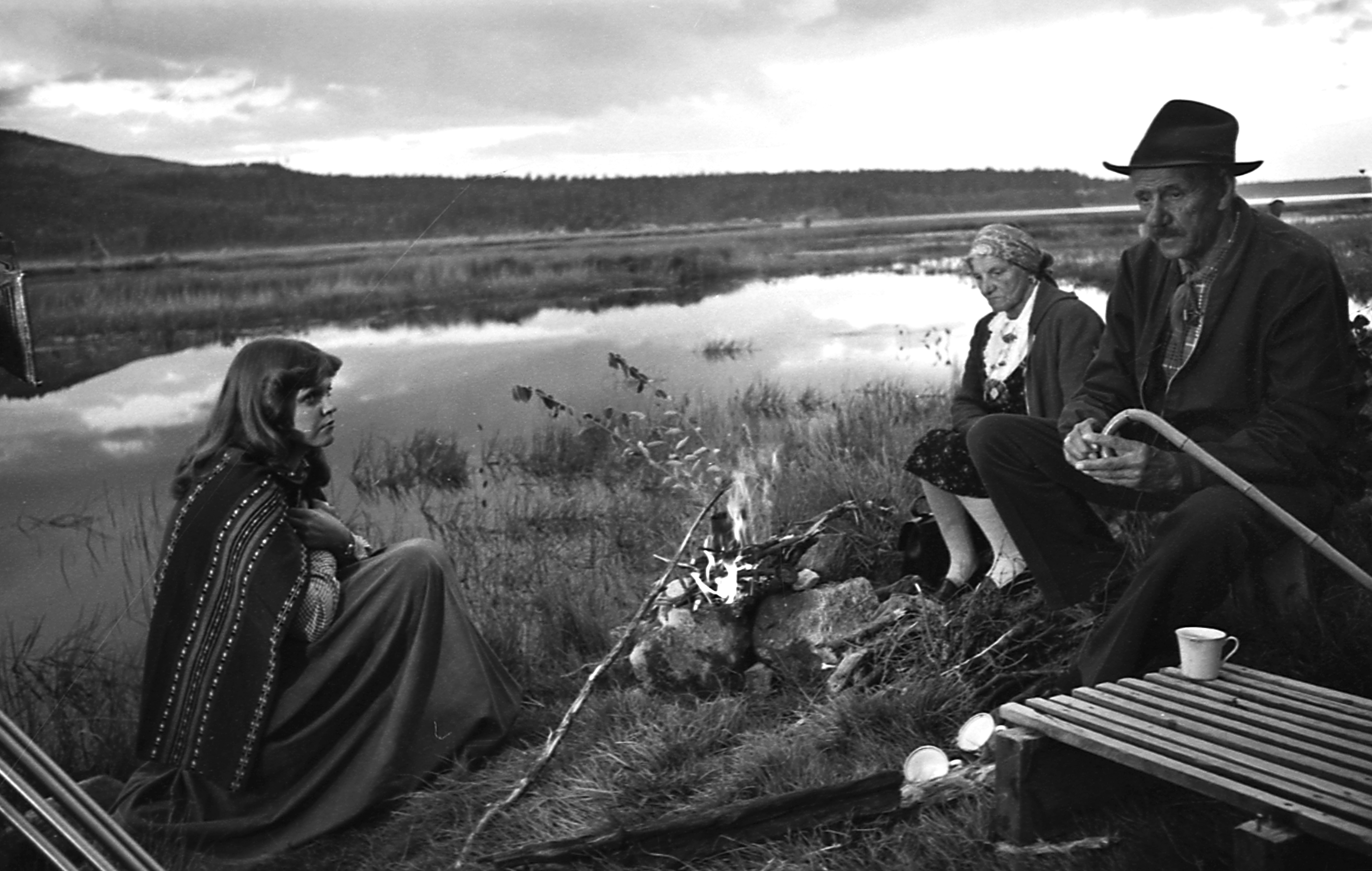 tre personer sitter ved et bål