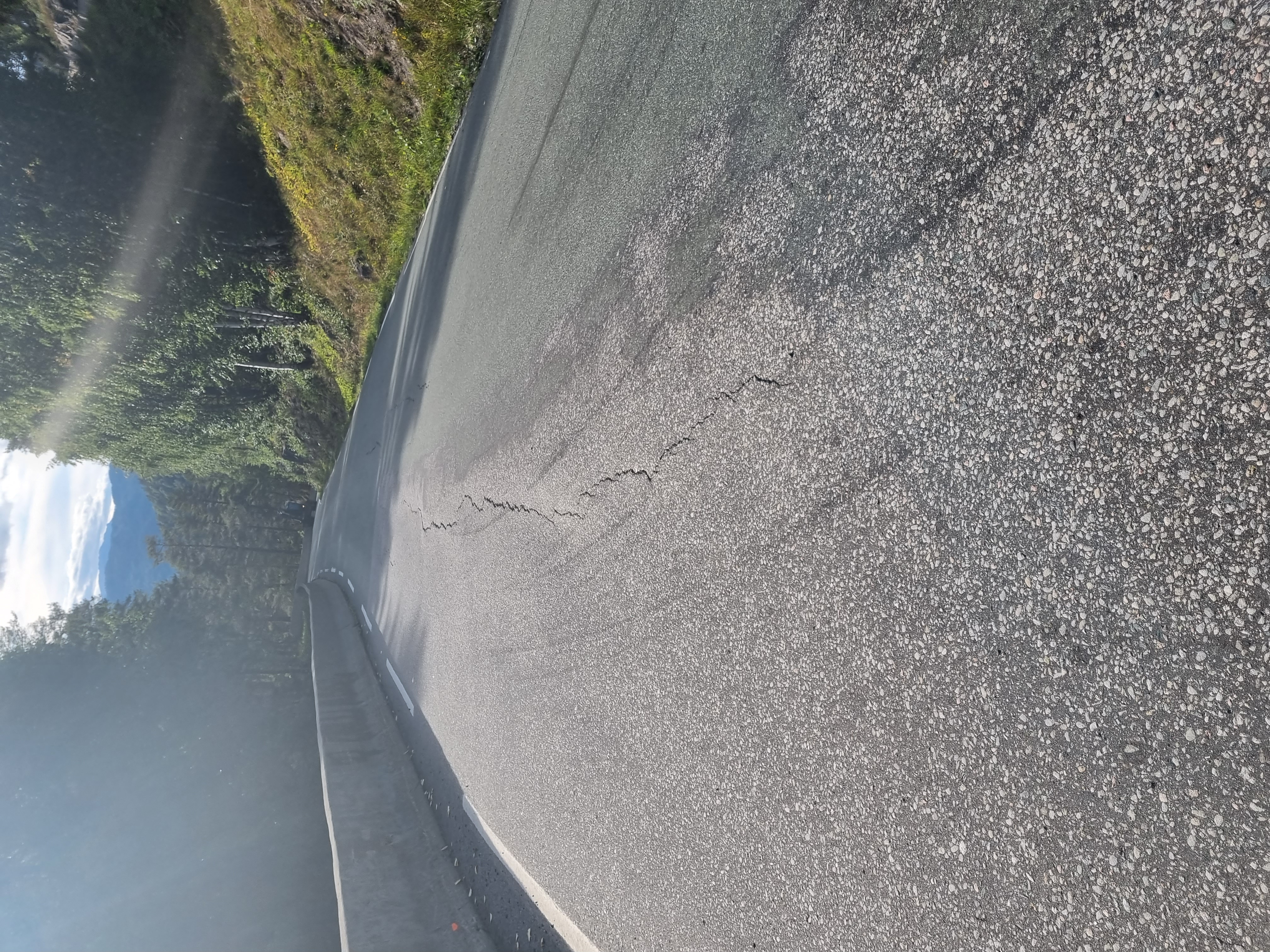 Vei som går innover i bildet. Ca på midten syns en oppsprekking i asfalten, samt en bulk som viser at veien har sunket på venstre side.
