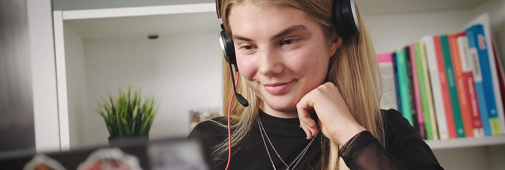 Jente foran PC med hodetelefoner