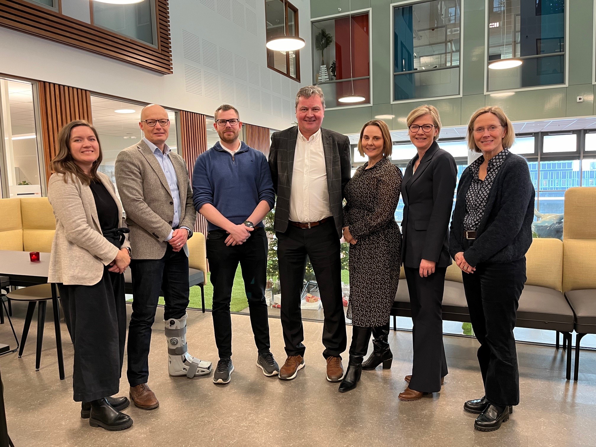 Gruppe med syv mennesker som smiler og ser i kamera