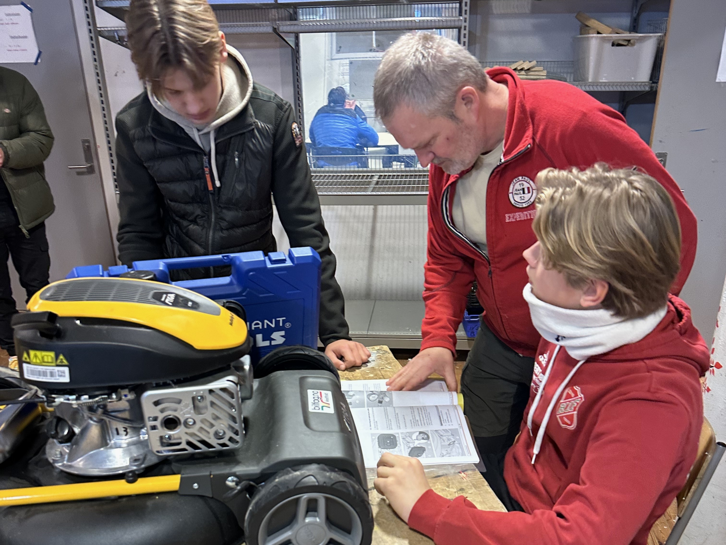 Elever jobber med gressklipper på verksted.