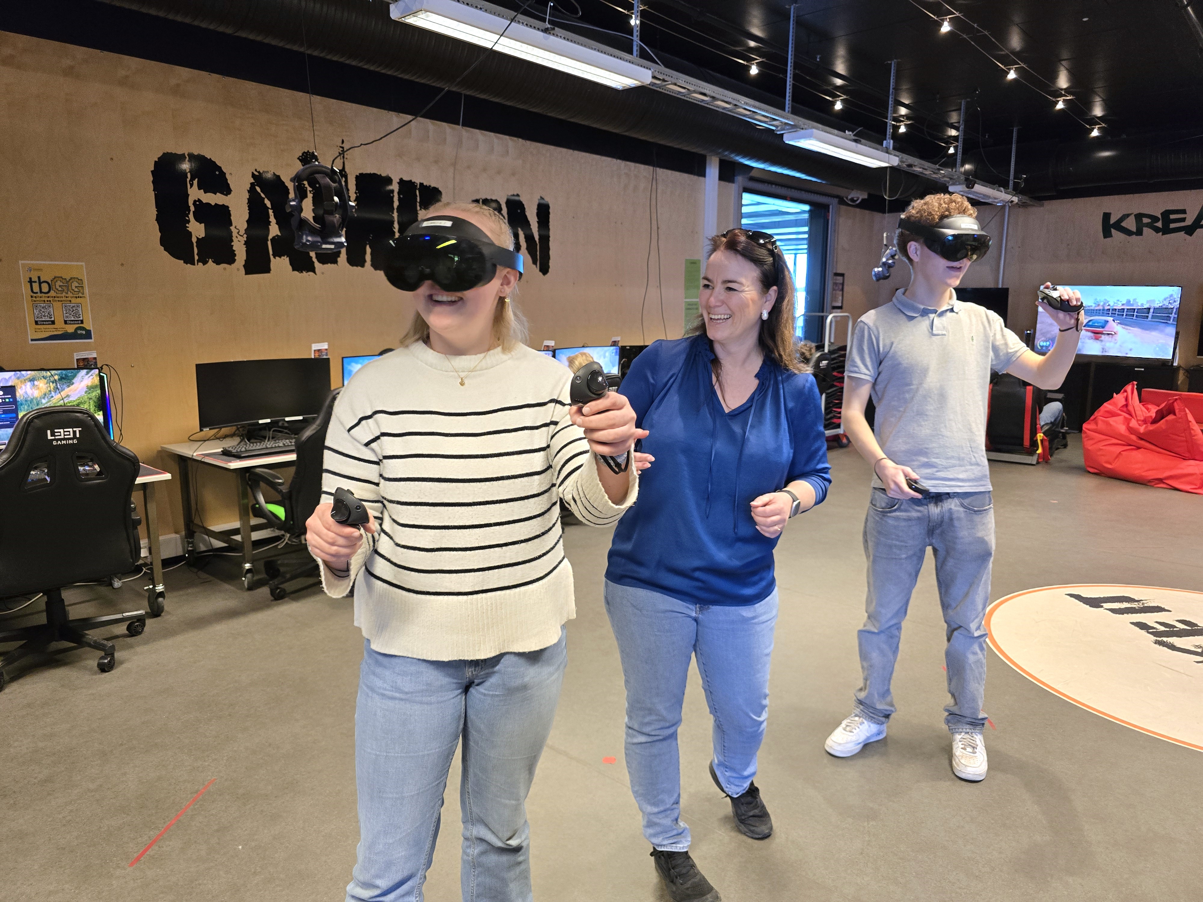 Tre personer i et gaming-rom. To har VR-briller.
