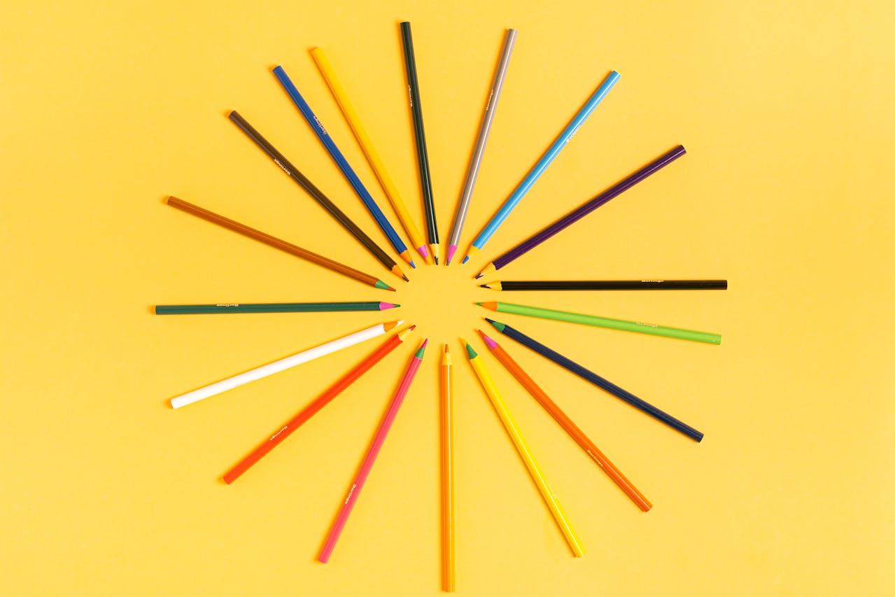 Fargeblyanter formet i sirkel som en sol, på gul bakgrunn.