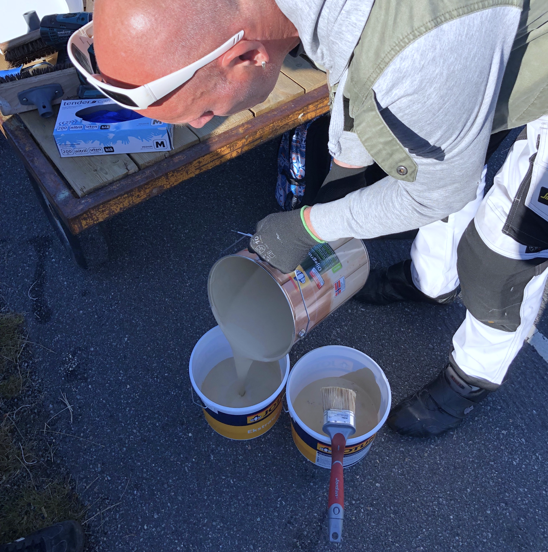 Maler tømmer maling i spann.