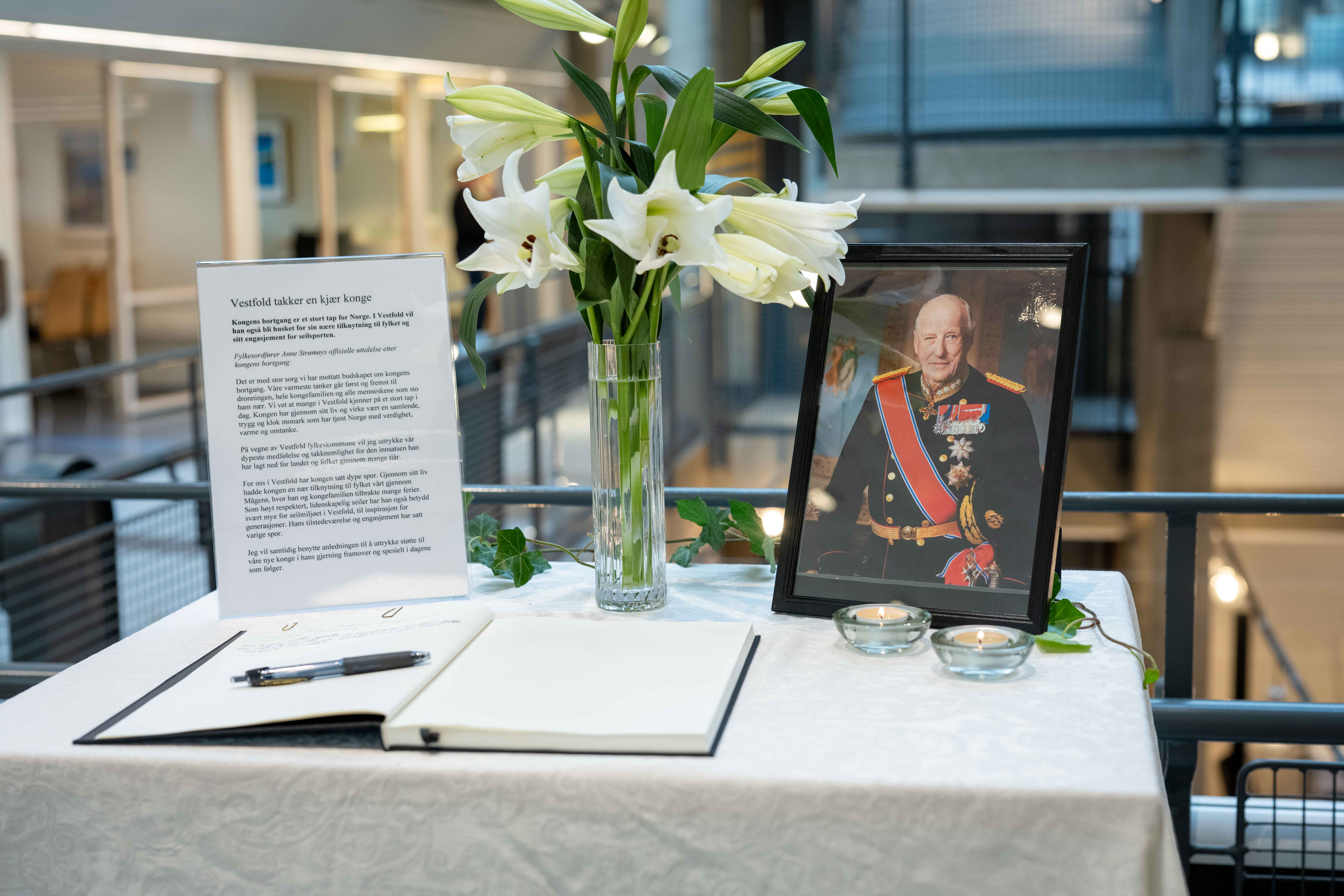 Bord med kondolanseprotokoll, blomst og bilde av Kong Harald