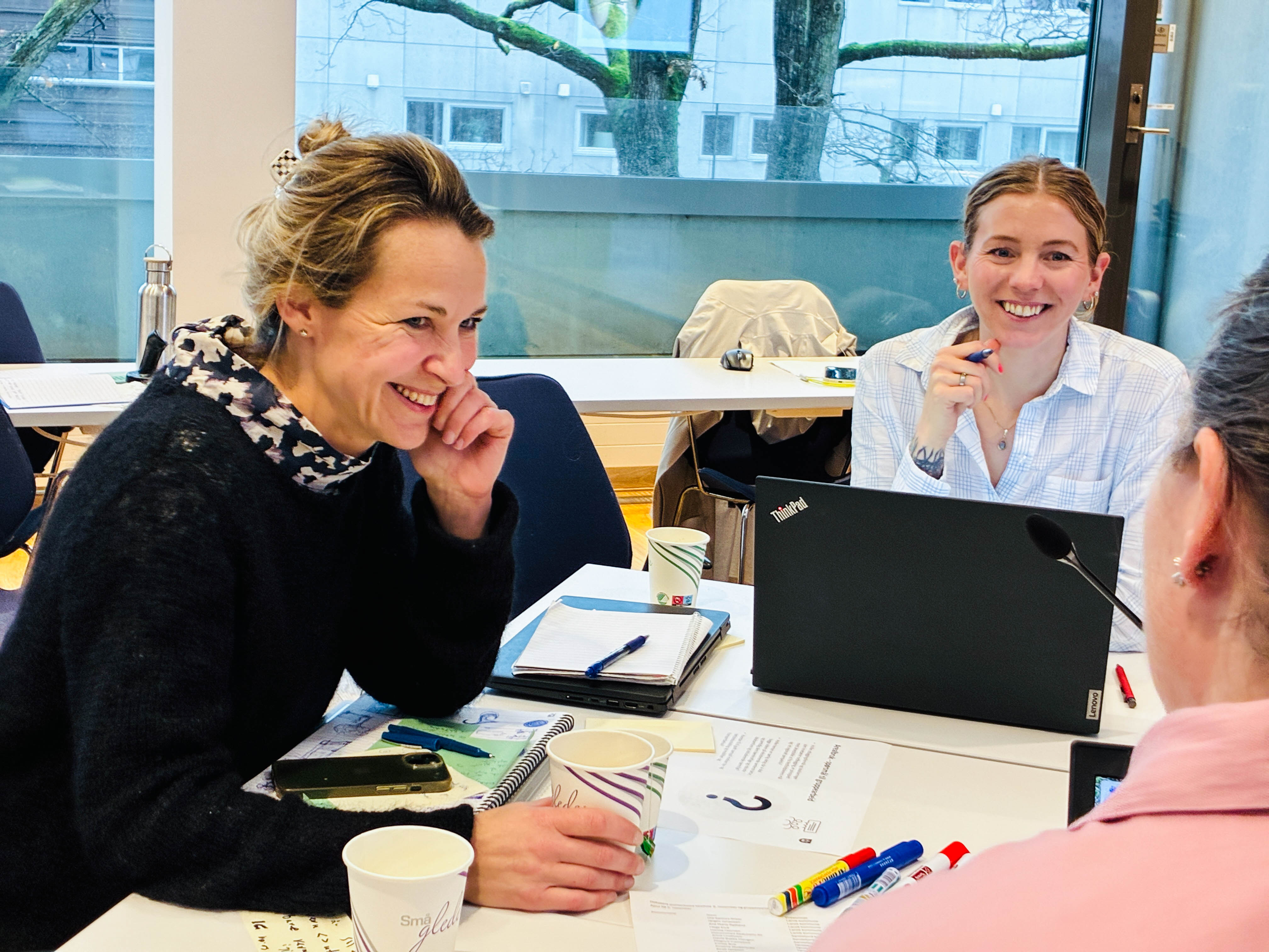 Tre personer i gruppearbeid rundt et bord